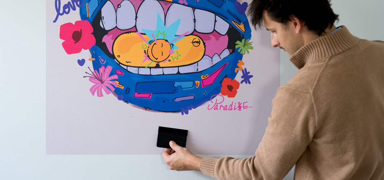 Person applying Stickablez peel and stick wall art with a squeegee tool in a college apartment