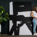 oman standing next to oversized black and white abstract wall art in a modern interior
