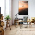 Oversized wall art of plane taking off at sunset hangs on white wall above sitting area in modern living room decorated minimally for Christmas.