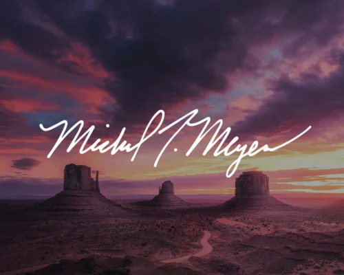 Pink sunset setting over desert with photographer Michael Meyers signature in white
