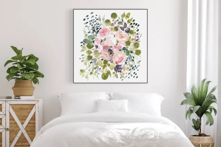 Large square wall art featuring watercolor painting of soft pink flower bouquet with lots of eucalyptus hangs on wall above bed n white bedroom.