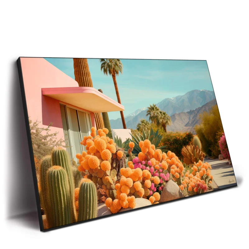Pink house with pink facade surrounded by vibrant cacti, tall palm trees, and mountains under a clear blue sky.