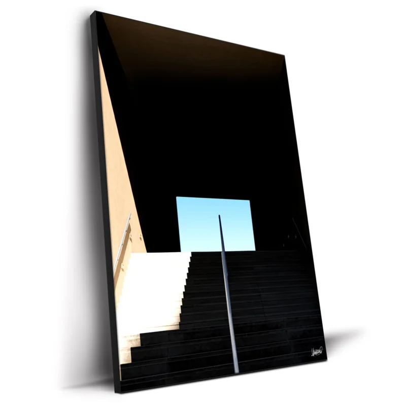 Staircase leading into darkness with a bright opening and clear blue sky, highlighting strong lines and shadows.