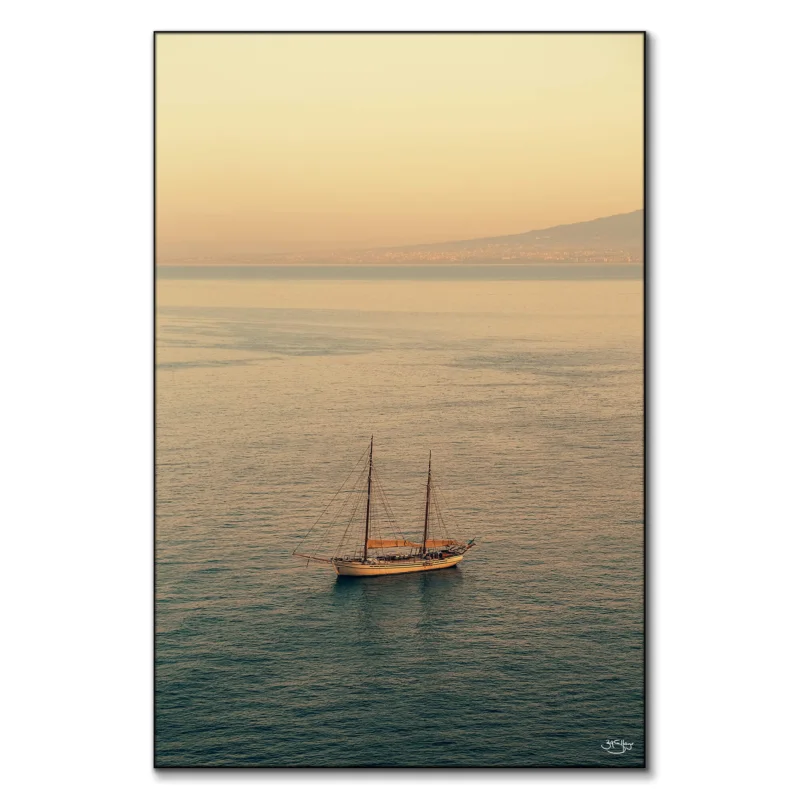 A sailboat on calm waters during a sunset in Italy.