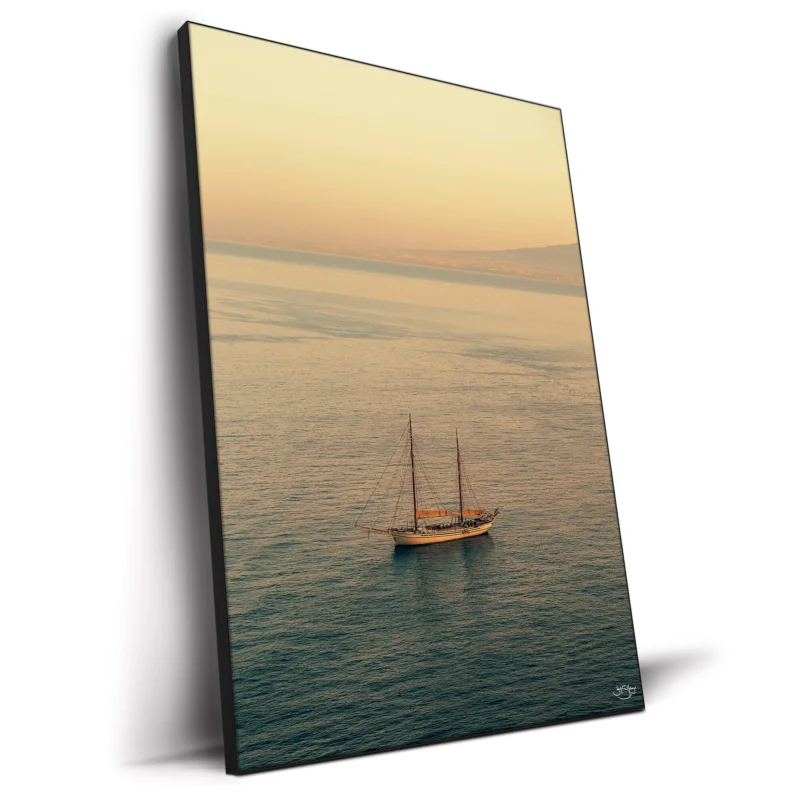 A sailboat on calm waters during a sunset in Italy.