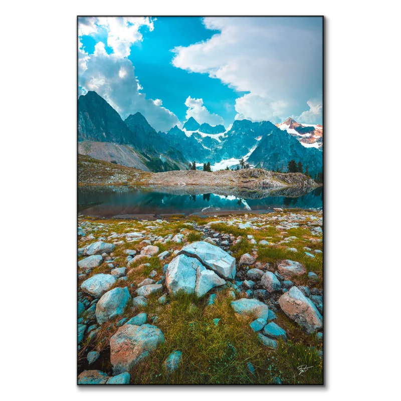 Clear mountain lake reflecting rugged terrain and towering peaks under a bright sky.