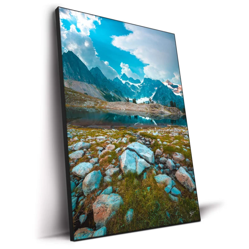 Clear mountain lake reflecting rugged terrain and towering peaks under a bright sky.