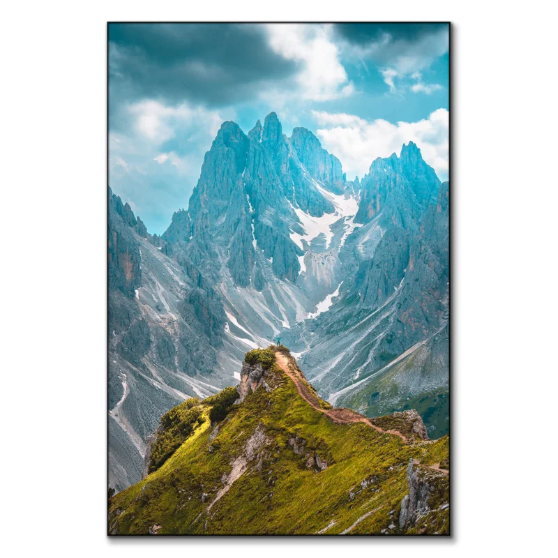 A person standing on a mountain peak, overlooking a vast and rugged landscape of valleys and peaks.